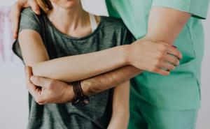 Ein Osteopath steht hinter einer Frau und behandelt sie.