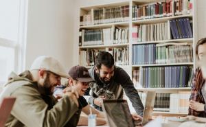 Eine Gruppe von lachenden Männern arbeitet an ihren Laptops.