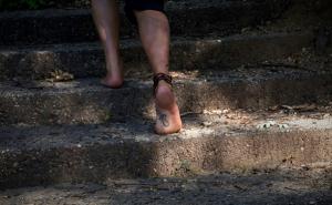 Eine Barfüßige Person geht eine steinerne Treppe im Freien hinauf.