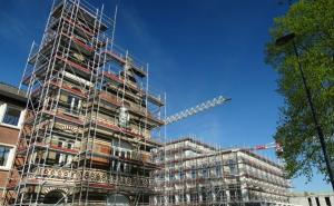 Mehrere Gebäude mit Baugerüst, im Hintergrund ein Baukran