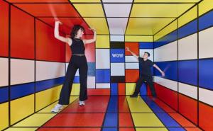 Ein Mann und eine Frau stehen in einem farbenfrohen Raum, der mit lebhaften Farben und kreativen Elementen gestaltet ist.  