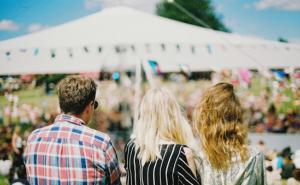 Drei Festivalbesucher stehen auf einer Wiese.