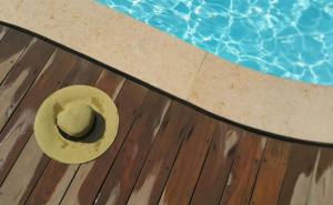 Ein Hut liegt auf einem Holzdeck neben einem Swimming Pool.  