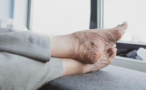 Die Füße einer älteren Person ruhen auf einer gepolsterten Fläche.