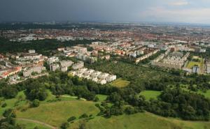 Luftaufnahme einer Stadt mit dicht bebauten Wohnhäusern und einer grünen Landschaft im Vordergrund