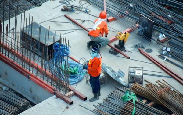 Zwei Bauarbeiter arbeiten auf einer Baustelle.