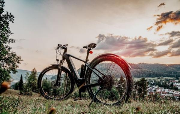 Ein E-Bike steht auf einem Hügel bei Sonnenuntergang.