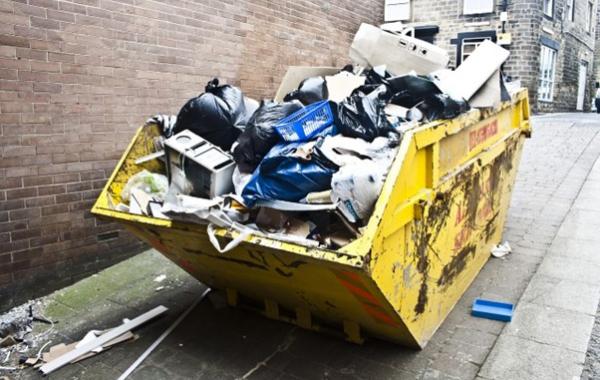 Gelber Müllcontainer, der mit verschiedenen Abfällen gefüllt ist