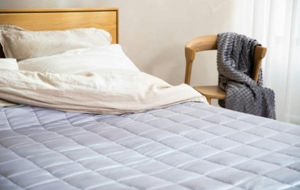 Bett mit einer gesteppten Tagesdecke und einem Stuhl daneben