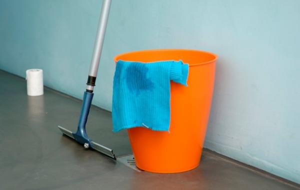 Putzeimer mit Wischer und Reinigungstuch auf einem Boden