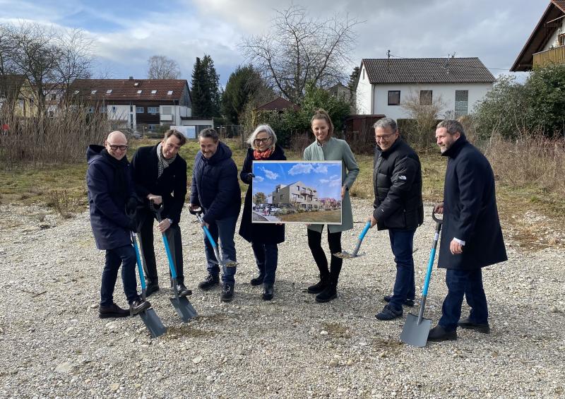 Personen mit Spaten und Plakat in der Hand auf Baustelle