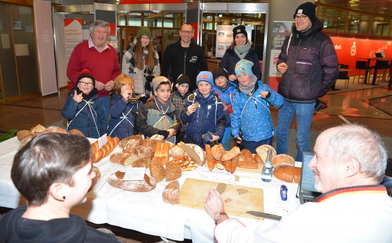 „Was macht der Mann da?“ zeigte der Bub aus der Vorschulgruppe der „Dinosaurier“ des Brucker Kinderhauses beim Betreten der Sparkasse mit ausgestrecktem Arm auf den Brot-Qualitätsprüfer des Deutschen Brotinstituts, Manfred Stiefel. Neugierig näherten sich die sieben Kinder mit ihren erwachsenen Betreuern dem „Brotstand“ im Foyer der Sparkasse, und verfolgten gespannt, was da geschah.