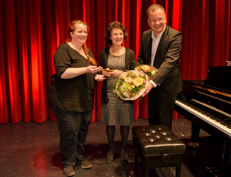 3 Personen bei Schlüsselübergabe und Verabschiedung mit Blumenstrauß