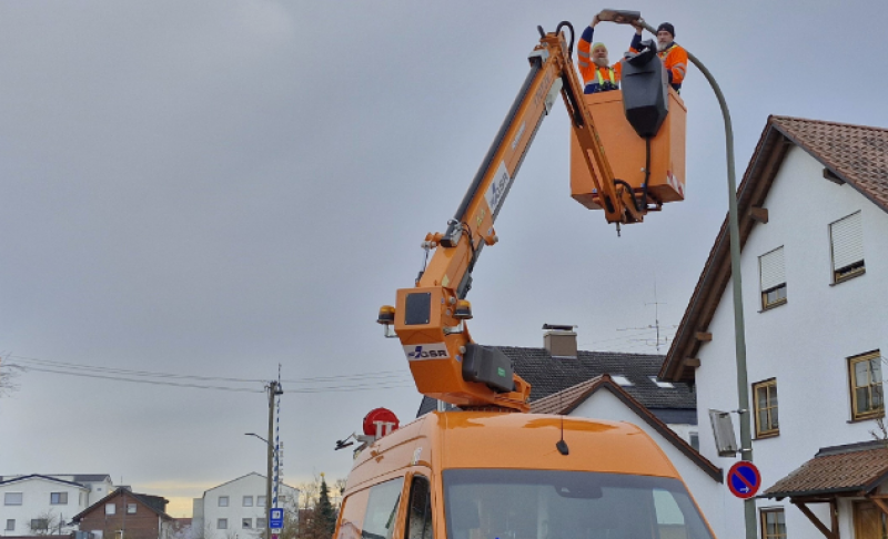 Uwe Fuchs und Dirk Birkholz (im Bild) tauschen die nächsten Monate zusammen mit Kollegen die alte Straßenbeleuchtung auf Maisachs Straßen gegen LED-Leuchten aus. Jason Podt, Klimaschutzbeauftragter der Gemeinde (links unten), freut das sichtlich: „Die Gemeinde spart dadurch auf lange Sicht viel Strom und damit Geld und auch Emissionen.“ 