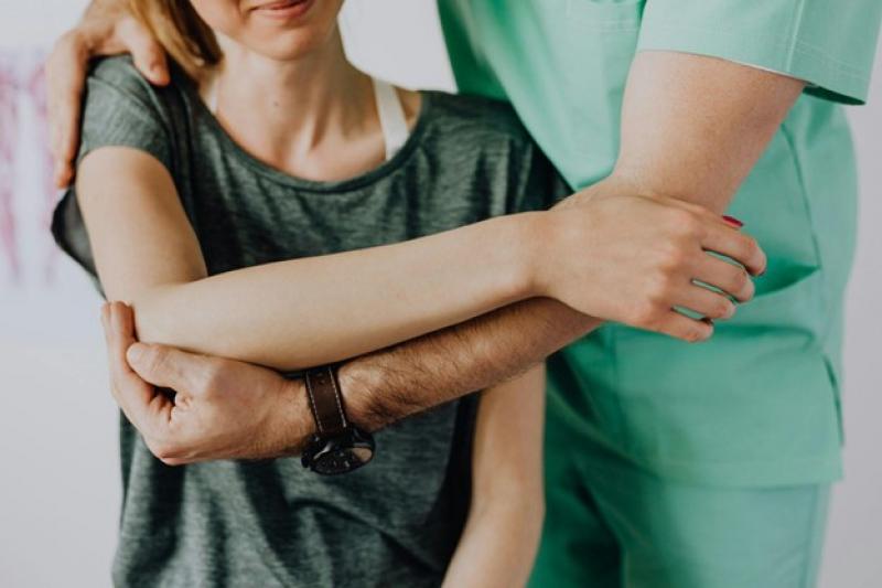 Ein Osteopath steht hinter einer Frau und behandelt sie.