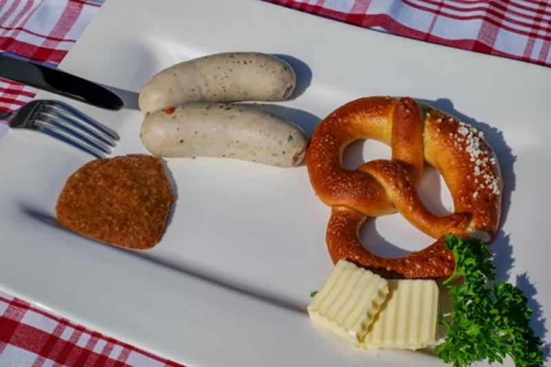 Brezel, Weißwürste und Senf auf einem Teller, typisch für die bayerische Küche