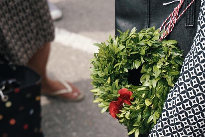 Eine Frau hält einen Buchsbaum-Kranz, der mit Blumen geschmückt ist.