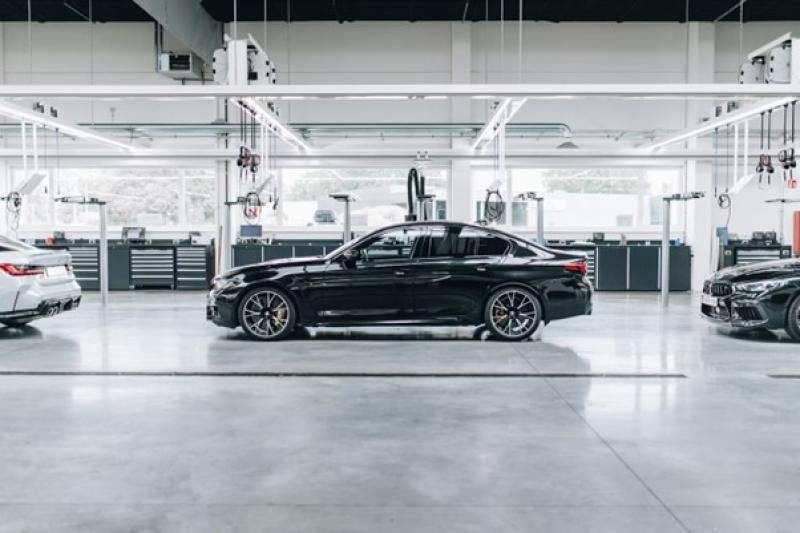 Schwarze Limousine in einer modernen, gut beleuchteten Werkstatt oder Produktionshalle