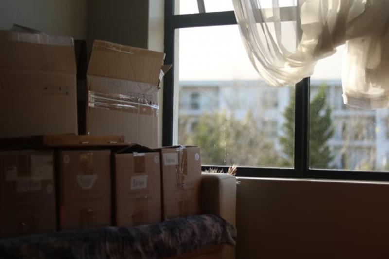 Umzugskartons stehen neben einem Fenster.