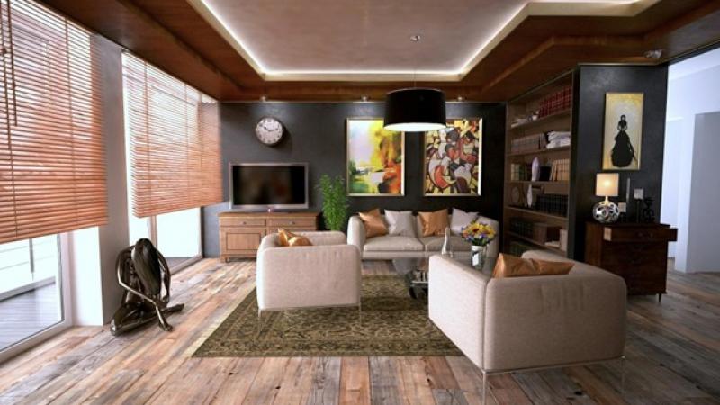 Wohnzimmer mit moderner Couchgarnitur, Holzregalen, Kunstwerken an der Wand und einem TV-Schrank. Der Raum hat Holzboden und große Fenster mit Holzjalousien.