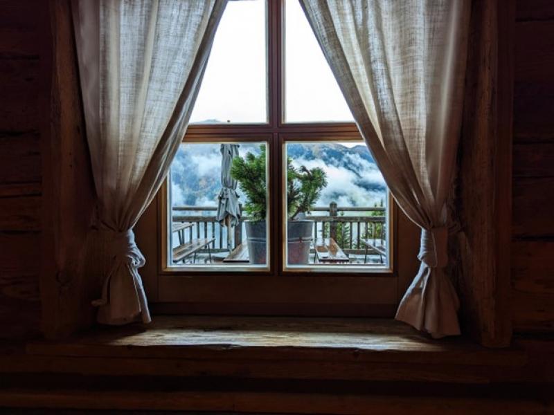 Ein Fenster mit Vorhängen und Blick auf die Berge