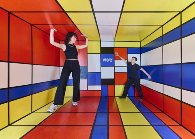 Ein Mann und eine Frau stehen in einem farbenfrohen Raum, der mit lebhaften Farben und kreativen Elementen gestaltet ist.  