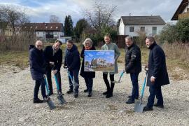 Personen mit Spaten und Plakat in der Hand auf Baustelle