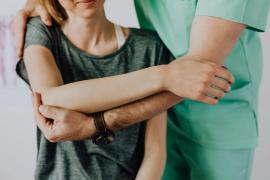 Ein Osteopath steht hinter einer Frau und behandelt sie.