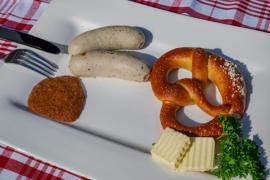 Brezel, Weißwürste und Senf auf einem Teller, typisch für die bayerische Küche