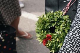 Eine Frau hält einen Buchsbaum-Kranz, der mit Blumen geschmückt ist.