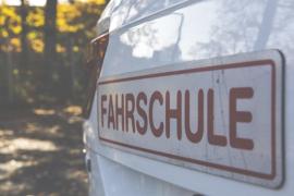 Fahrzeug von hinten mit einem Schild "Fahrschule"