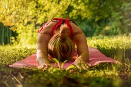 Eine Frau macht Yoga-Übungen auf einer grünen Wiese.