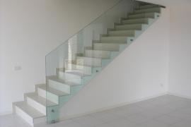 Eine Treppe mit einem Glasgeländer in einem weißen Raum