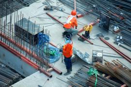 Zwei Bauarbeiter arbeiten auf einer Baustelle.