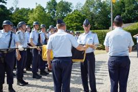 Der Kommandeur der Offizierschule, Brigadegeneral Gero von Fritschen (l.) und Oberstleutnant Andreas Seebörger als bisheriger Lehrgruppenkommandeur rollen gemeinsam die Truppenfahne der II. Lehrgruppe der OSLw in einem feierlichen Akt ein und verhüllen sie anschließend mit einem schwarzen Stoffsack.