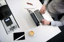 Ein Mann sitzt an einem Schreibtisch und arbeitet an einem Laptop.