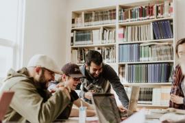 Eine Gruppe von lachenden Männern arbeitet an ihren Laptops.