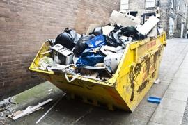 Gelber Müllcontainer, der mit verschiedenen Abfällen gefüllt ist