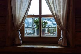 Ein Fenster mit Vorhängen und Blick auf die Berge