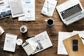 Ein Schreibtisch mit einem geöffneten Laptop und diversen Büroartikeln