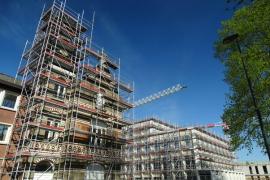 Mehrere Gebäude mit Baugerüst, im Hintergrund ein Baukran