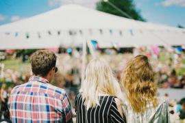 Drei Festivalbesucher stehen auf einer Wiese.