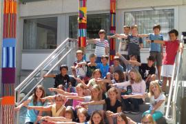 Stolz zeigen die Kinder auf ihr kunterbuntes Werk: Die Säulen am Eingang der Grundschule wurden umhäkelt.