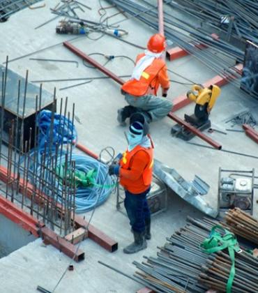 Zwei Bauarbeiter arbeiten auf einer Baustelle.