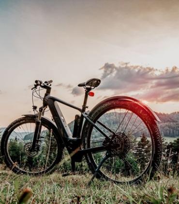Ein E-Bike steht auf einem Hügel bei Sonnenuntergang.