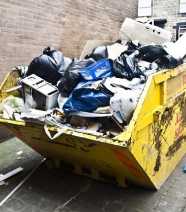 Gelber Müllcontainer, der mit verschiedenen Abfällen gefüllt ist