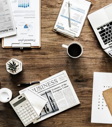 Ein Schreibtisch mit einem geöffneten Laptop und diversen Büroartikeln